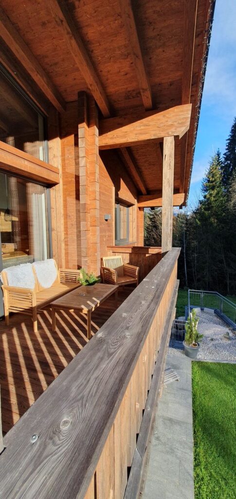 Sonniger Holzbalkon eines Zeitfrei Chalet Apartments mit Blick zum Wald