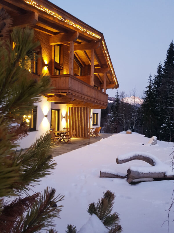 Chalet im Schnee bei Winterabendbeleuchtung und Sternenhimme