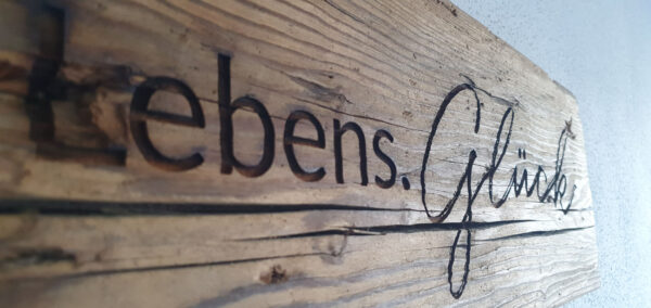 Holzschild mit Schriftzug Lebens.Glück verbreitet natürlichen Charme im Chalet
