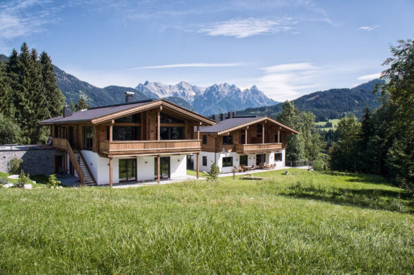 Vorderseite des Chalets mit großer Liegewiese und Bergen