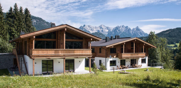 Blick übers Grundstück auf Chalet und Bergpanorama