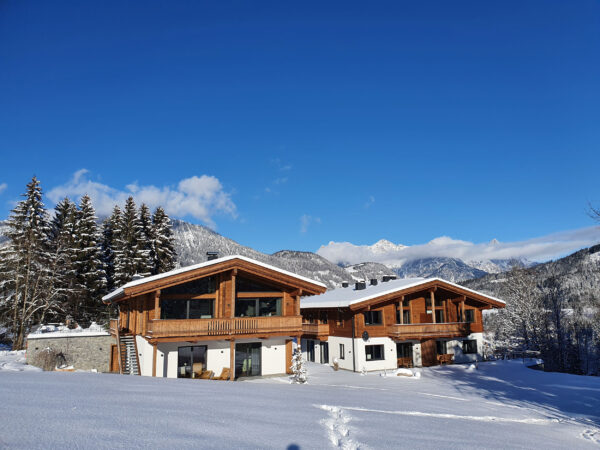 Sonniger Wintertag: Chalet vor tiefblauem Himmel und Alpenpanorama