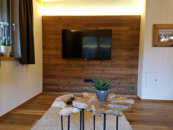 Gemütlicher Wohnbereich mit TV, Altholzwand und Couchtischen im Chalet