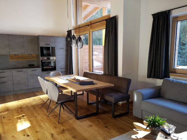 Lichtdurchfluteter Wohnraum mit Sofa, Esstisch und Panoramafenstern