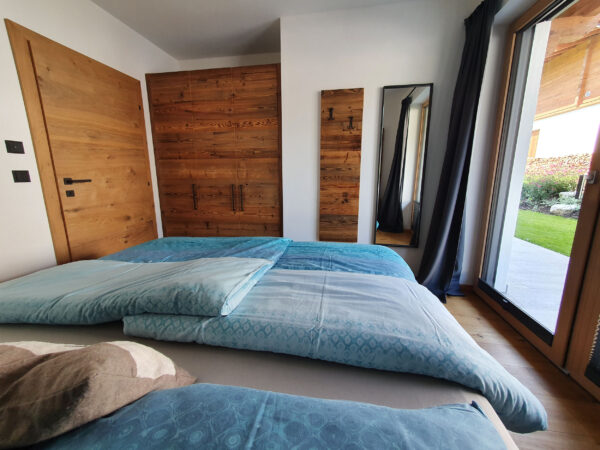Schlafzimmer mit türkisfarbener Bettwäsche, Boxspringbett und Terrassentür zum Garten
