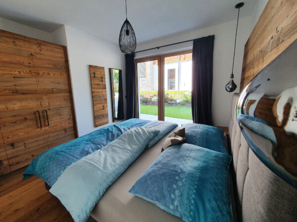 Schlafzimmeransicht, Boxspringbett, Spiegel und Pendelleuchte unter gemütlicher Altholzbalkendecke