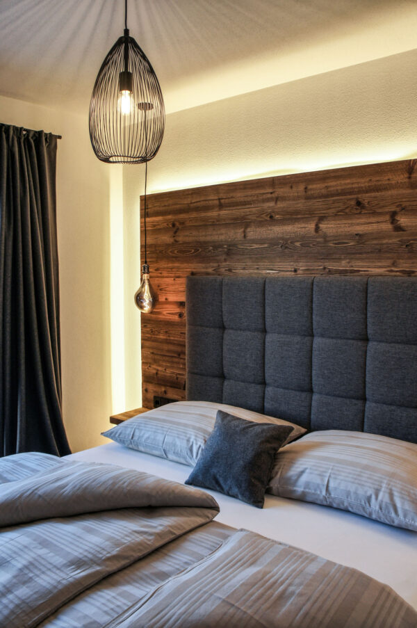 Boxspringbett mit Pendelleuchte und indirekter Beleuchtung