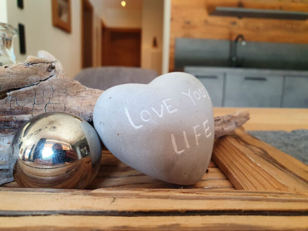 Dekotablett mit Love-Stone Herz, glänzenden Kugeln und Naturmaterialien am Tisch
