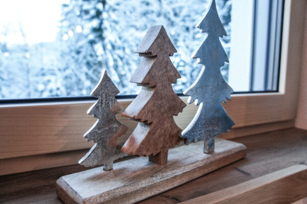 Dekorative Holz-Bäume auf Fensterbank mit Schneepanorama