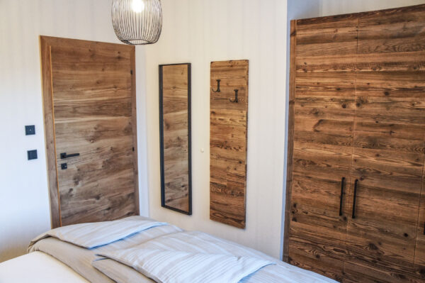 Altholz-Wand, Spiegel und Boxspringbett im Chalet