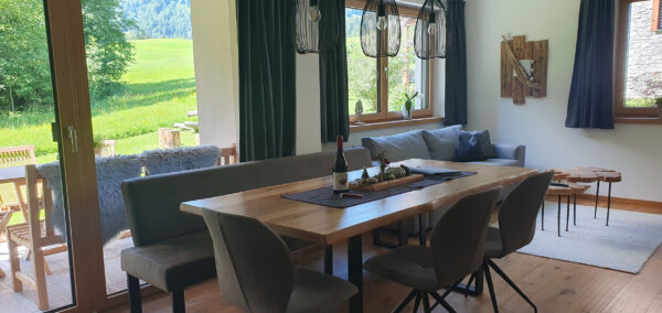 Großer Massivholztisch im Wohnraum, Blick auf Garten durch bodentiefe Fenster