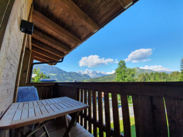 Balkontisch mit Aussicht auf Bergwiese und blauen Himmel