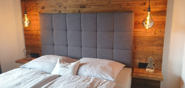 Boxspringbett in Abendlicht mit weichen Kissen und Holzdecke