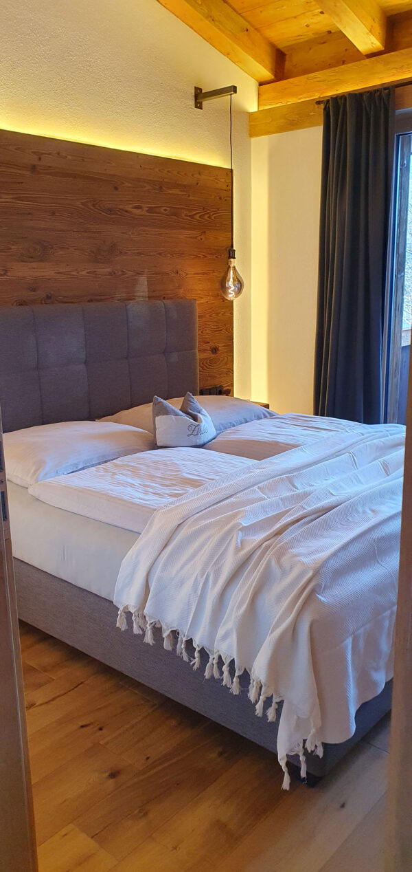 Frisch gemachtes Boxspringbett unter Holzbalkendecke