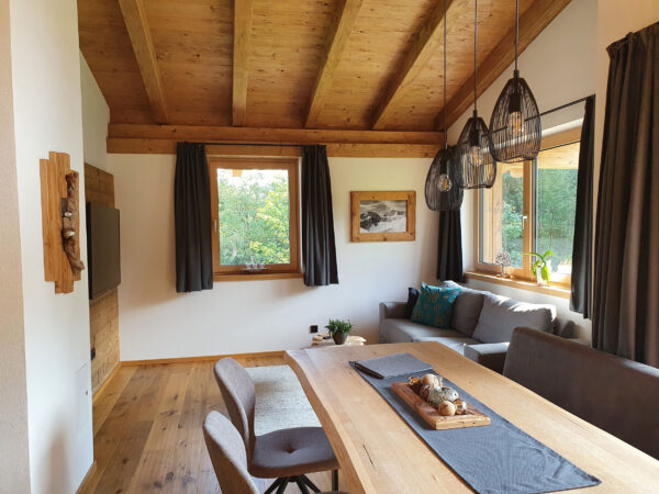 Großes Sofa, Essbereich und Bergblick in lichtdurchflutetem Wohnraum