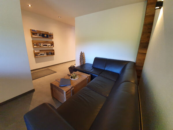 Wohnzimmer im Chalet zeitfrei Fieberbrunn mit gemütlichem Ledersofa und dekorativen Holztischen – Entspannung pur in den Kitzbüheler Alpen.